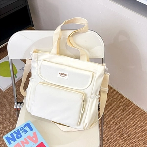 Detail view of large cream canvas tote with multi-pockets and adjustable shoulder strap