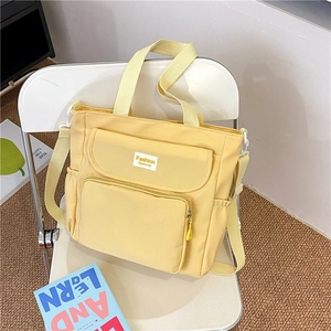 Detail of yellow canvas tote bag with multiple pockets and adjustable shoulder strap