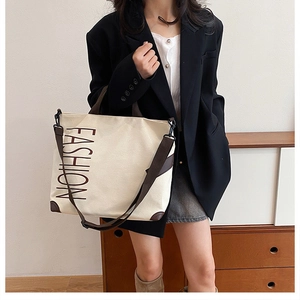 Detail of off-white canvas tote with FASHION print and adjustable brown straps