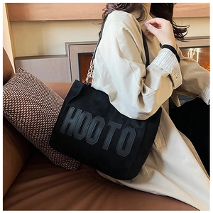 Detail of black plush tote bag with HOOTO letter embroidery and chain strap detail