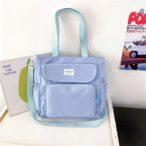 Detail view of light blue versatile tote bag with adjustable straps and front zip pockets