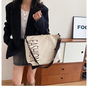 Detailed shot of beige canvas tote bag with brown leather trim and fashion text logo