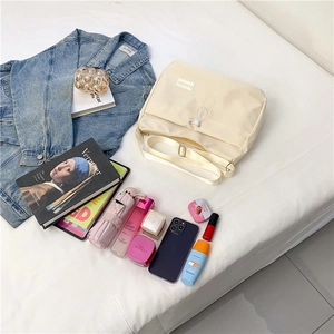 Lifestyle view of cream canvas dumpling bag with fashion label and daily essentials