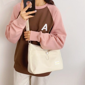 Detail of beige nylon crossbody dumpling bag with drawstring and Fashion label on model