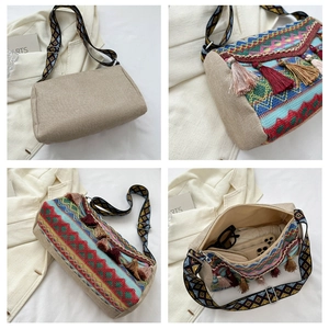 Detail view of ethnic tote bag showing colorful tassels, embroidery and wide woven strap