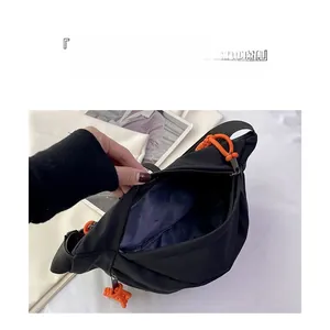 Detailed macro view showing the spacious interior and orange zipper pulls of the black chest bag