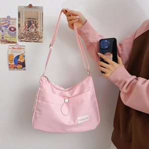Detail of pink half-moon messenger bag showing fabric texture and fashion label