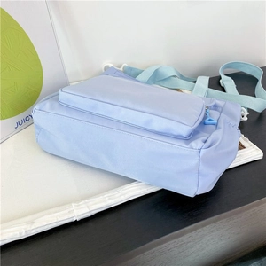 Close-up of waterproof light blue nylon crossbody bag with zipper front pocket detail