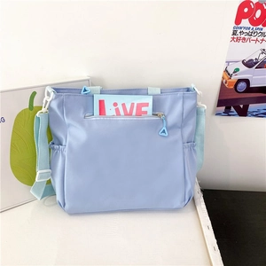 Detail view of light blue nylon tote bag showing the side elastic pocket and strap