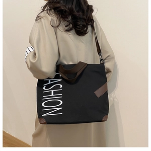 Detail of fashion print canvas tote bag with brown leather straps and metal hooks