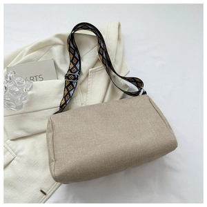 Detail of oatmeal woven shoulder bag with a colorful geometric patterned strap and tassels