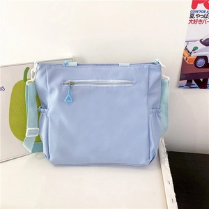 Detail of light blue nylon crossbody bag with waterproof fabric and front zipper pocket