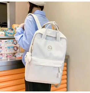 Side view of a white waterproof nylon backpack featuring cute plush bear charms on the side