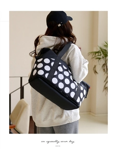 Detailed view of polka dot travel bag with bottom compartment carried by a model