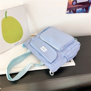 Detail view of light blue nylon bag showing multi-pocket design and fashion label