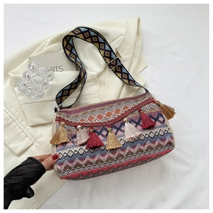 Detail of bohemian knit shoulder bag with colorful geometric patterns and fringe charms