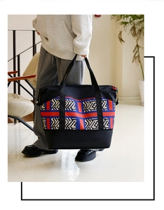 Close-up of stylish travel tote featuring red and blue stripes with geometric patterns