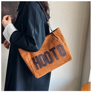 Detail of vintage brown suede tote bag with HOOTO letter patch and metal chain strap