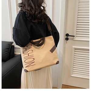 Detailed side view of the beige canvas tote bag with brown straps worn on the shoulder