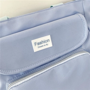 Detail of light blue fabric tote featuring Fashion Dream label and durable metal zipper