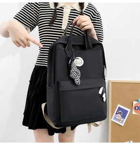 Close-up of black nylon backpack featuring decorative charms and ergonomic straps