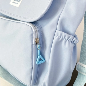 Detail view of light blue nylon backpack showing silver zipper and fashion label