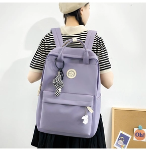 Detail of purple student backpack with checkerboard knot and rabbit charm on model back