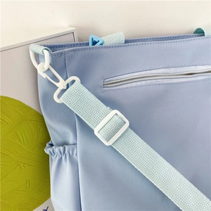 Detailed close-up of light blue tote bag stitching and white hook hardware detail