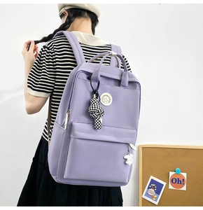 Close-up of light purple nylon backpack with cute charms and double handles for school