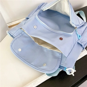 Detailed interior of blue nylon tote showing main zipper pocket and two magnetic front pockets