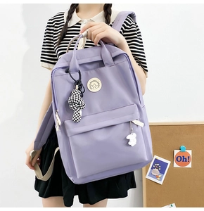 Detail of purple nylon backpack featuring a mountain logo and cute decorative pendants