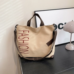 Minimalist beige canvas tote bag with brown straps and red fashion lettering text