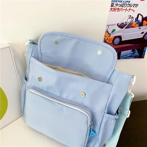 Close-up of light blue canvas bag featuring multi-pocket design and metal magnetic closure