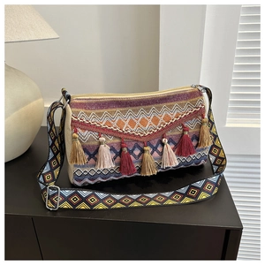 Detail of ethnic woven bag featuring colorful tassel charms and wide geometric shoulder strap