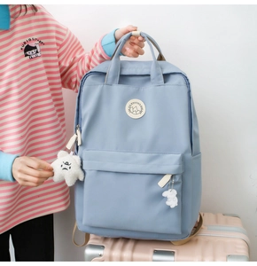 Close-up of light blue nylon backpack with star and bunny charms on pink luggage