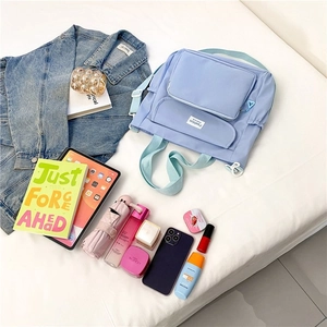 Flat lay of light blue nylon backpack showing spacious compartments and daily essentials