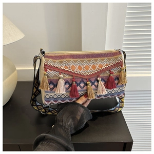 Detail of colorful woven bohemian crossbody bag with tassel fringe and geometric wide strap