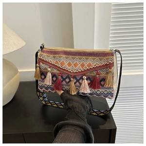 Detail of bohemian knit bag with colorful fringe and wide geometric woven strap