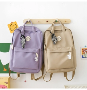 Detail of Korean style nylon backpacks in purple and beige with decorative charms