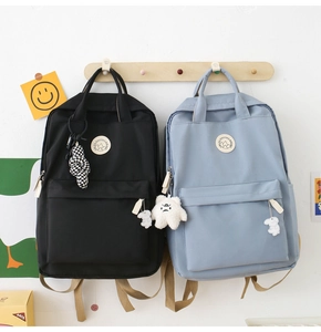 Detail view of black and light blue canvas backpacks with cute charms and mountain badge