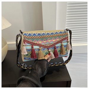 Detail of colorful woven bohemian bag featuring multi-color tassels and patterned strap