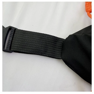Detail shot of the durable nylon strap, plastic buckle, and orange accent on black chest bag
