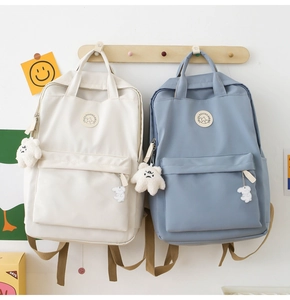 Detail of minimalist cream and blue backpacks featuring cute bear and rabbit accessories