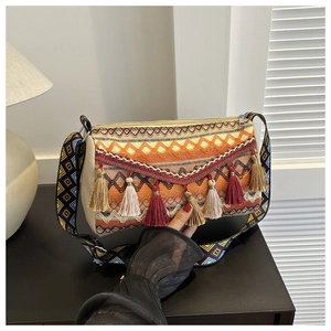 Close-up of bohemian woven shoulder bag featuring ethnic patterns and colorful tassels