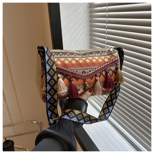 Detail of bohemian woven bag featuring colorful tassel charms and patterned wide strap