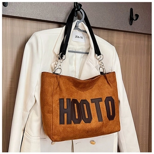 Close-up of brown suede tote bag with HOOTO letter patch and metal chain strap