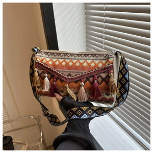 Detail of bohemian woven bag with geometric patterns, colorful tassels and wide strap