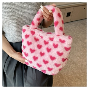 Detail of soft pink plush handbag featuring dark red heart patterns and fluffy texture