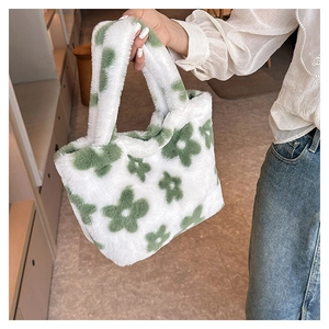 Detailed view of the soft white faux fur tote bag with dark green floral patterns