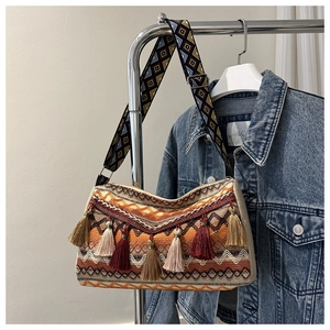Bohemian woven shoulder bag with vibrant tassels and geometric patterned wide strap